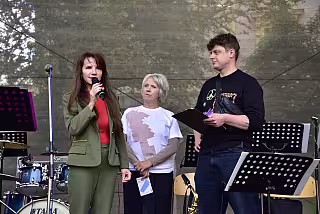 Ředitelka Alice Šmídová na pódiu, moderátor a sponzoři Chevak a Karlovarský kraj
