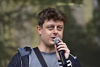 Moderátor uvádí na pódiu