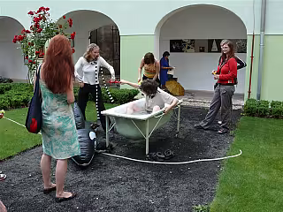 Skupina dětí hraje ping-pong na zahradě vedle bílé budovy.
